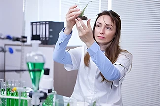 A woman in a lab coat examines a plant, highlighting her meticulous nature and dedication to scientific research.